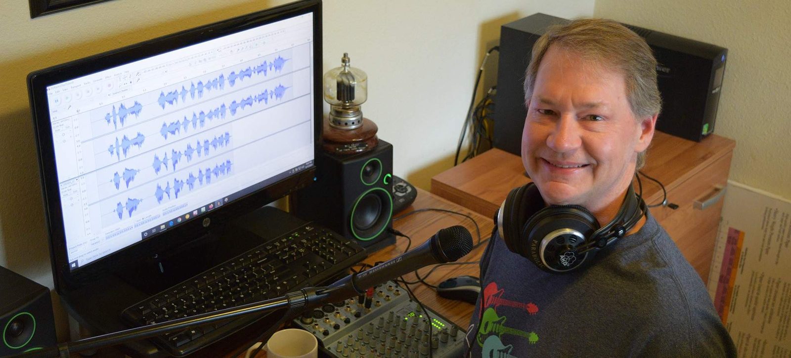 Bill Grady at his studio desk, headphones around his neck, an audio editor open on the monitor beside him